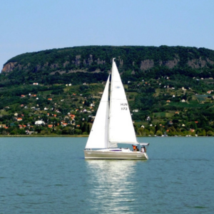 Sailboat gliding across Lake Balaton in the countryside Hungary with the volcanic hills of Badacsony in the background.