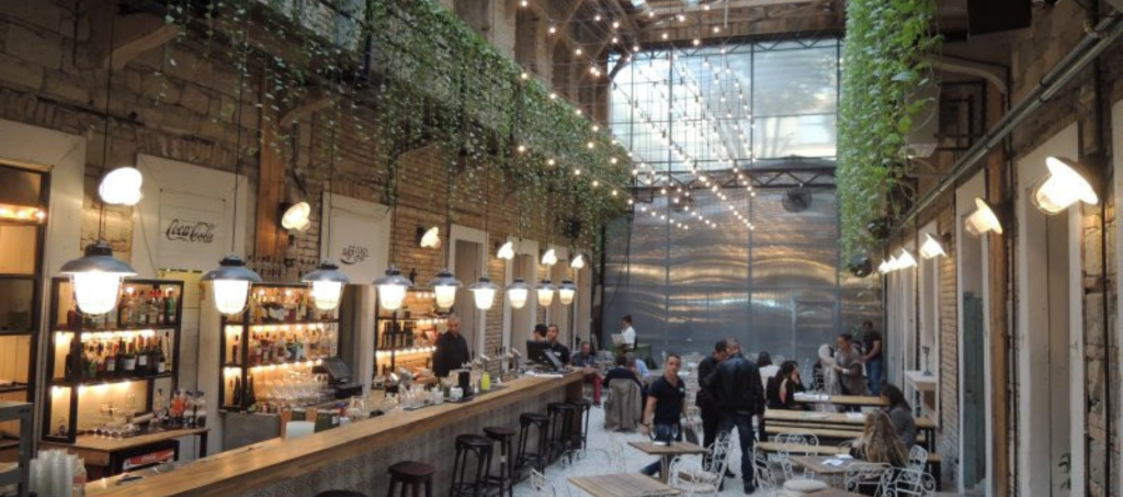 Mazel Tov Budapest interior with fairy lights, greenery, and lively evening guests