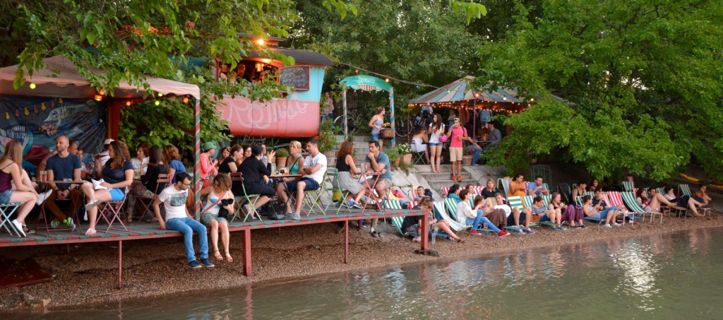 People relaxing at open-air bars on Római Part by the Danube.
