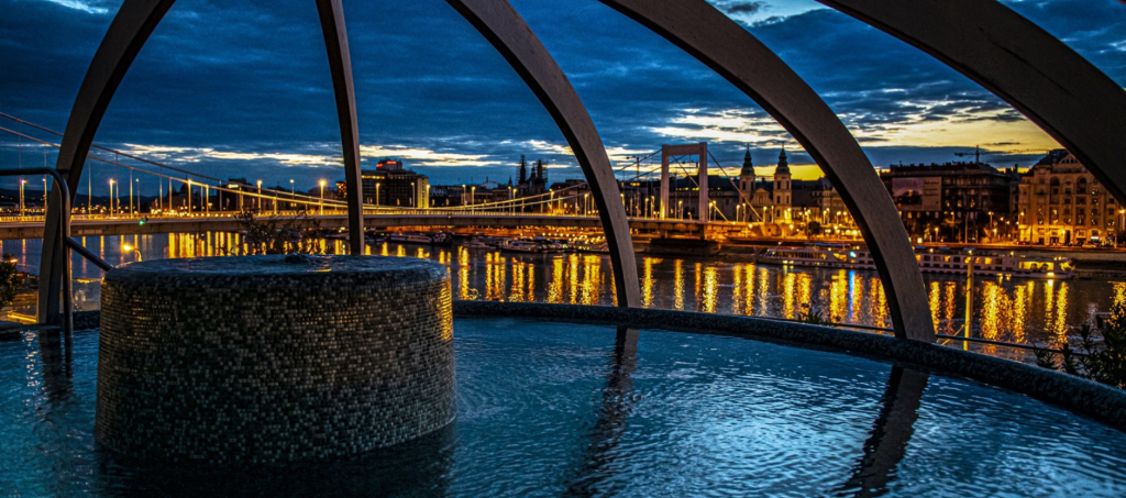 Rooftop thermal pool at Rudas Bath overlooking the Danube at night.