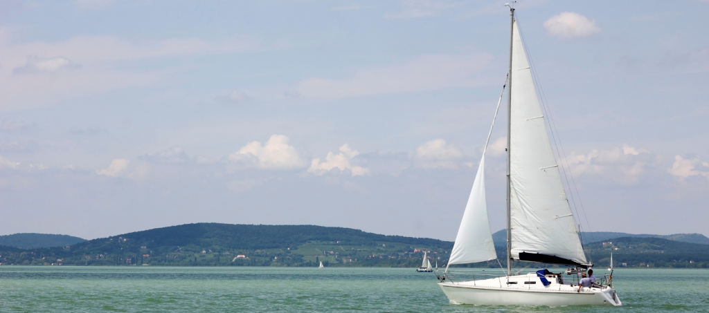 Sailboat gliding across Lake Balaton with the volcanic hills of Badacsony in the background.