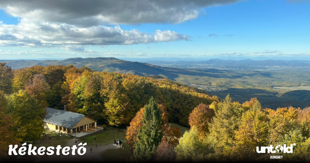 Sweeping view from Kékestető showing the rolling Mátra Mountains covered with autumn foliage and dramatic clouds.